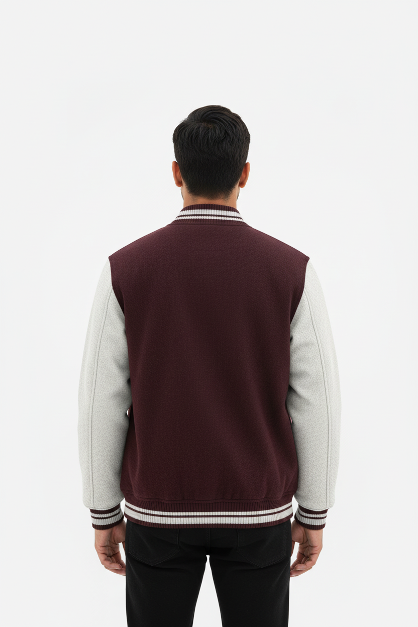 Man wearing maroon and light gray varsity jacket standing with back to camera on white background