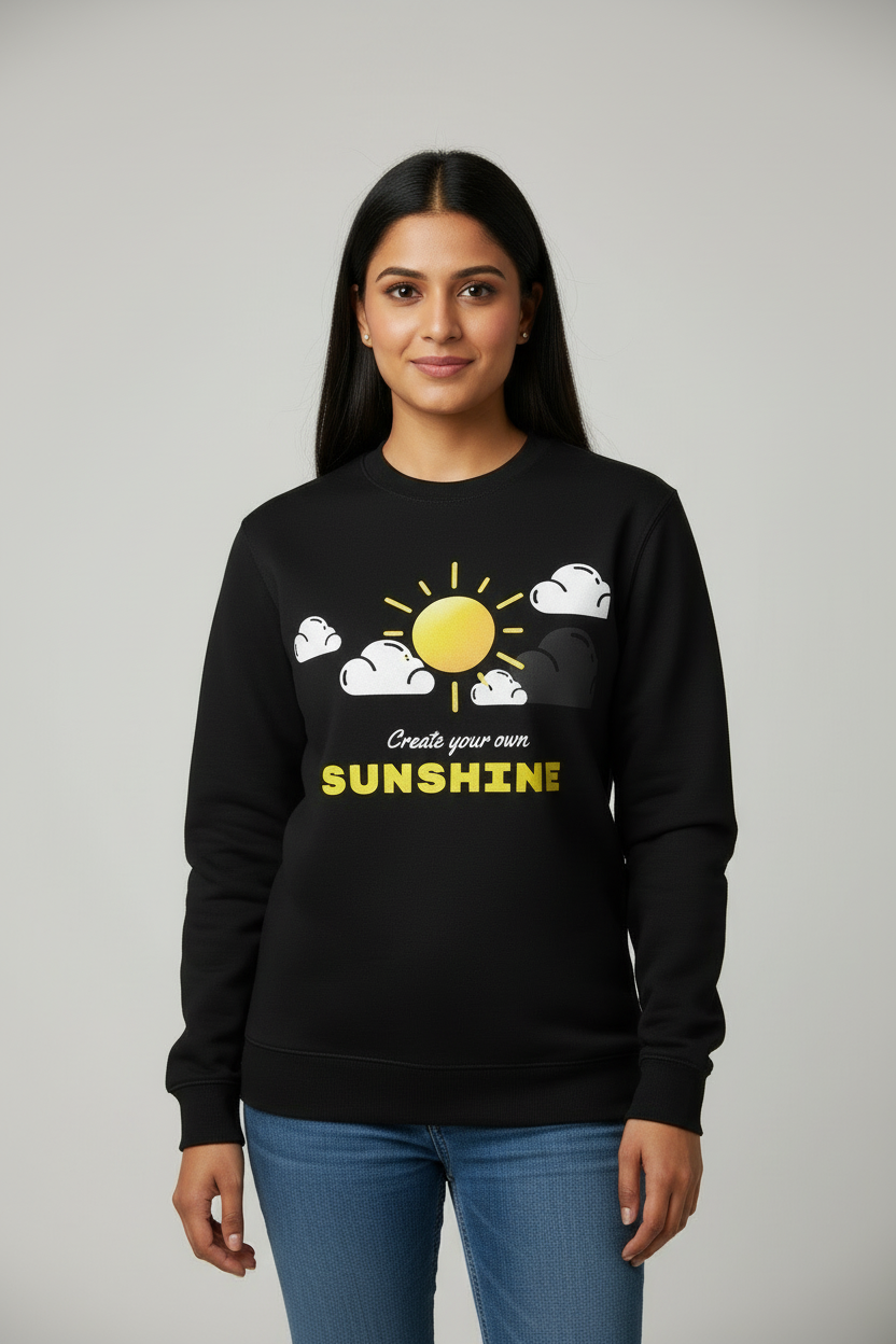 Woman wearing black sweatshirt with yellow sun and white clouds graphic saying Create your own SUNSHINE