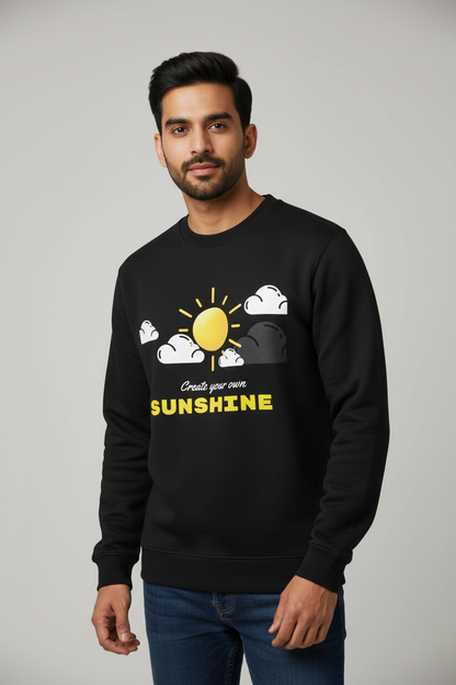 Man wearing black sweatshirt with yellow sun and clouds graphic and text Create your own SUNSHINE