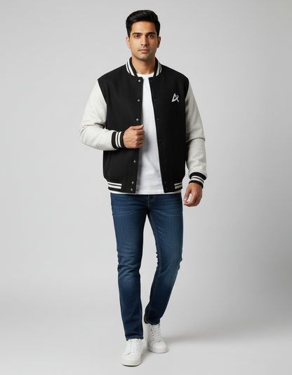 Man wearing black and gray varsity jacket with white t-shirt, blue jeans, and white sneakers